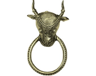 Può includere: Un batacchio per porta in metallo dorato a forma di testa di toro con dettagli intricati. Il batacchio ha un anello per tirare.