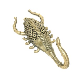 May include: A gold metal scorpion wall hook with a detailed woven design. The scorpion's tail is curled up and forms a hook.