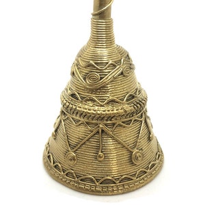 Pu&ograve; includere: Una campana color oro con intricati dettagli avvolti in filo metallico e motivi decorativi. La campana ha una base svasata e un lungo e sottile manico. Il design include forme geometriche e motivi a spirale, creando una superficie strutturata.