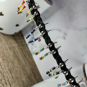 May include: A set of colorful beaded earrings with silver posts. The earrings are displayed on a black cord.