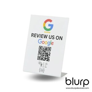 May include: White tabletop sign with a Google logo, the text "REVIEW US ON Google", a QR code, and the text "TAP OR SCAN YOUR LOGO HERE". The sign has a white base with the text "blurp www.blurpdevices.com".