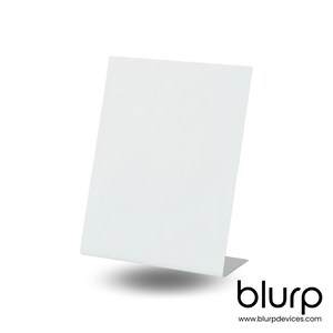 May include: White acrylic display stand with a rectangular base and a slanted surface. The stand is designed to hold small items, such as jewelry or other small objects.
