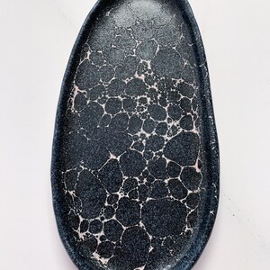 May include: A black oval ceramic serving tray with a crackled glaze and pink accents.