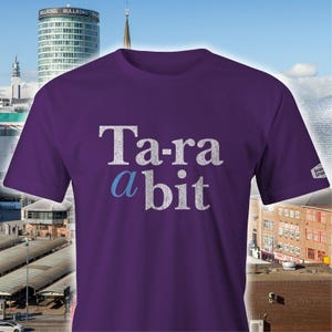 Op de afbeelding: Paars T-shirt met de tekst "Ta-ra a bit" in witte en blauwe letters.