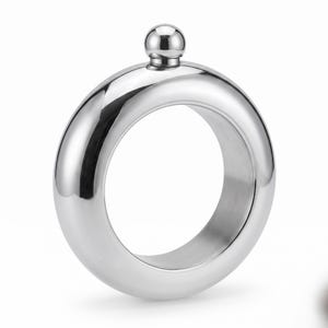 May include: A circular, ring-shaped silver-colored metal flask with a polished, reflective surface. The flask features a hollow center and a small, spherical screw-top cap located at the very top of the rounded, tubular metal frame.