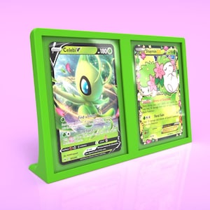 May include: A green card display stand with two Pokemon cards. The card on the left is a Celebi V card with a green background and the card on the right is a  Magmortar card with a green background.