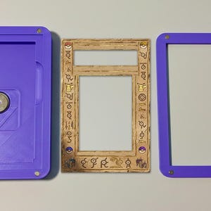 May include: A three-part set comprising a purple case with a magnetic closure, a decorative frame with symbols, and a purple frame. The case and frames are made of plastic. The decorative frame is light brown.