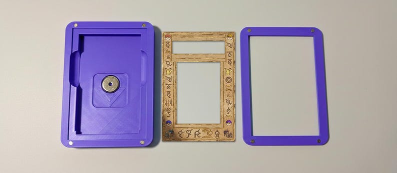 May include: A three-part set comprising a purple case with a magnetic closure, a decorative frame with symbols, and a purple frame. The case and frames are made of plastic. The decorative frame is light brown.