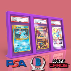 May include: Three Pokemon trading cards are displayed in a purple acrylic case. The cards are encased in protective plastic sleeves. The cards are from the Japanese set, "2000 P.M. Japanese Gold Star Final Battle Holo Promo/Battle." The cards feature the Pokemon, "Blastoise", "Mewtwo", and "Charizard".