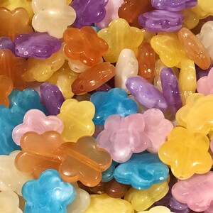 May include: Assortment of colorful plastic flower-shaped beads. The beads are in shades of blue, pink, yellow, orange, and purple.