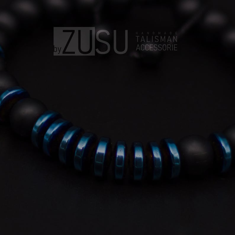 May include: A black and blue beaded bracelet with the text "ZUSU by HANDMADE TALISMAN ACCESSORIE".