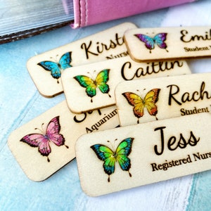 May include: Wooden name tags with butterfly designs and glitter accents. The tags feature names like "Kirst Nurse", "Caitlin", "Jess Registered Nurse", "Rachel Student", and "Emily Student".