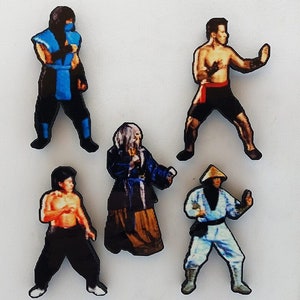 May include: Five colorful figurines of characters from the video game Mortal Kombat. The characters are Sub-Zero, Scorpion, Liu Kang, Kitana, and Raiden. The figurines are made of wood and are painted in bright colors.