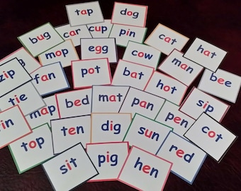 May include: A set of colorful flashcards with various words printed on them, including "zip", "bug", "tie", "tin", "tap", "dog", "car", "cup", "pin", "mop", "fan", "egg", "pot", "cow", "cat", "man", "bat", "hot", "map", "bed", "mat", "pan", "pen", "top", "ten", "dig", "sun", "red", "sit", "pig", "hen", "cot", "hat", "bee", "sip".