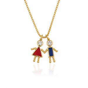 May include: A gold-tone necklace featuring two connected pendant figures. One figure has a red triangular body, and the other has a blue rectangular body. Both figures have round heads set with clear stones and are suspended from a delicate chain.