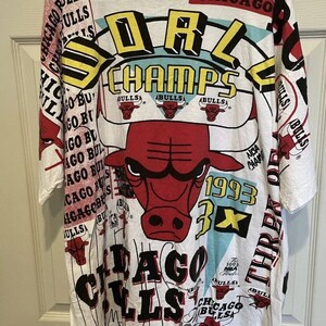 May include: White t-shirt with a colorful graphic print featuring the Chicago Bulls logo, the text "World Champs", and the year "1993".