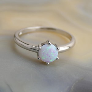 May include: A silver ring with a white opal gemstone set in a prong setting.