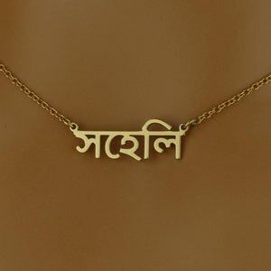 May include: A gold chain necklace with a pendant that says "সাহসী" in Bengali script.