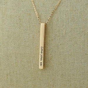 May include: A gold necklace with a vertical bar pendant engraved with the text "Love you xx".