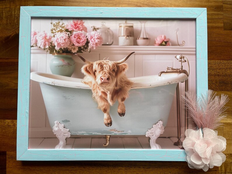 May include: A Highland cow taking a bath in a vintage clawfoot tub with pink flowers in the background. The tub is light blue and has white feet. The cow is brown and white and has a fluffy coat.
