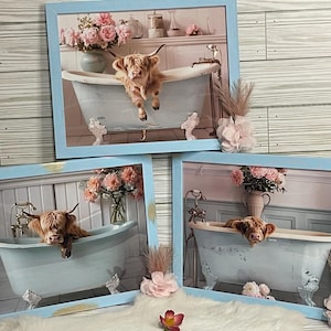 May include: Three framed prints of Highland cows in a bathtub with pink flowers. The frames are light blue with gold accents.
