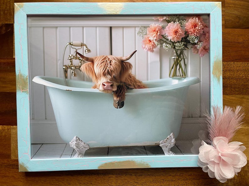 May include: A Highland cow takes a bath in a light blue bathtub with white feet. The cow is brown and white and has its head resting on the edge of the tub. The bathtub is in a white bathroom with white tile walls and a white tiled floor. There are pink flowers in a vase in the background.