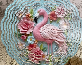May include: A metal wind spinner with a pink flamingo and floral design. The spinner has a blue background and is layered with multiple circles.