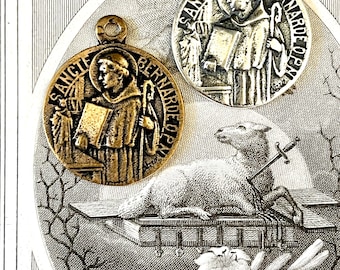 May include: Two antique silver and gold medallions with the inscription "Sancte Bernarde De Oen" and an image of Saint Bernard of Clairvaux. The medallions are surrounded by a black and white image of a lamb, books, and flowers.
