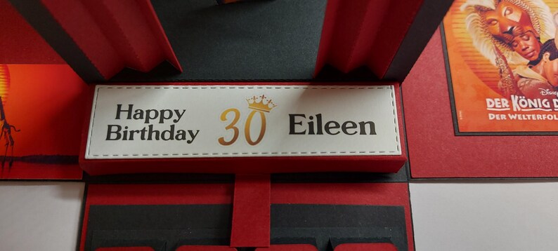 Puede incluir: Tarjeta de cumplea&ntilde;os hecha a mano con un dise&ntilde;o rojo y negro. La tarjeta presenta el texto "Happy Birthday 30 Eileen" en letras doradas y negras. La tarjeta tiene un dise&ntilde;o desplegable y una corona decorativa.