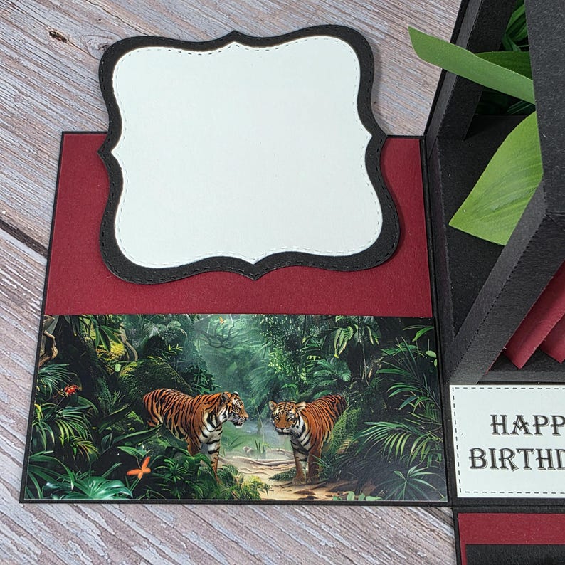 Puede incluir: Tarjeta de cumplea&ntilde;os hecha a mano con tem&aacute;tica de jungla. La tarjeta presenta un fondo rojo, una etiqueta blanca decorativa con un borde negro y una escena de jungla con dos tigres. Tambi&eacute;n se ven las palabras "HAPPY BIRTHAY".