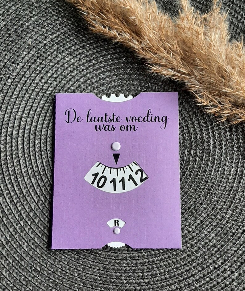 May include: A purple card with the text "De laatste voeding was om" and a clock face with a black hand pointing to the number 11.