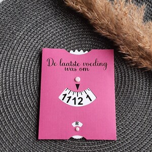 May include: A pink card with the text "De laatste voeding was om" and a clock face with the time 17:12.
