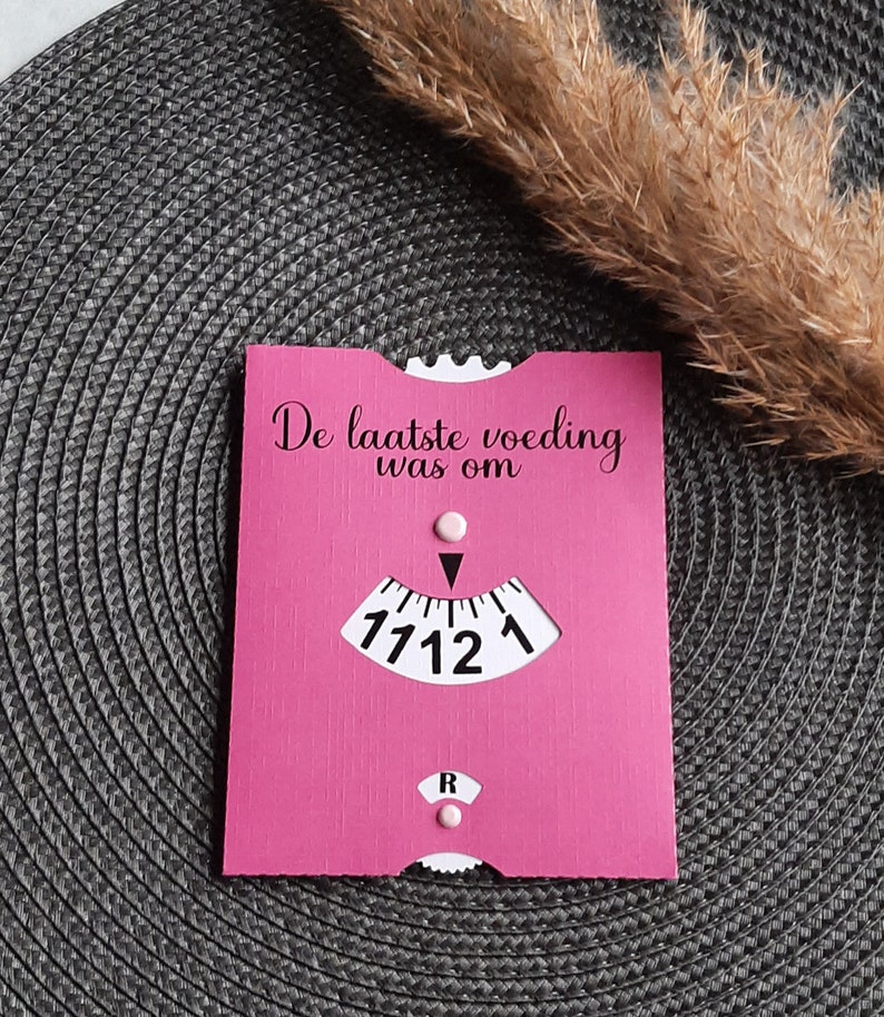 May include: A pink card with the text "De laatste voeding was om" and a clock face with the time 17:12.