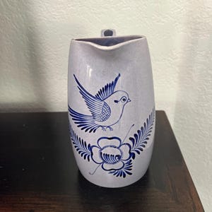 May include: A light blue ceramic pitcher with a blue and white bird and flower design.
