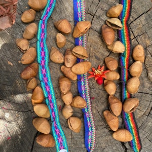 May include: Three colorful woven bracelets with tags that say "Made in Peru" and a pile of brown seed pods.