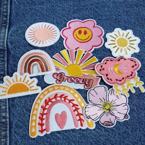 Puede incluir: Una colección de parches bordados de colores para planchar que representan arcoíris, soles, flores y nubes. Los parches tienen un estilo retro y groovy y son perfectos para añadir un toque personal a la ropa, las bolsas u otros accesorios.