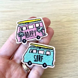 May include: Two embroidered iron-on patches featuring a vintage van with a surfboard on top. One patch is pink with the word "HAPPY" on the side and the other is blue with the word "SURF" on the side.