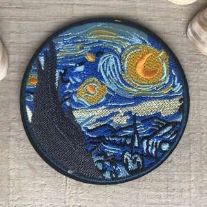 Puede incluir: Un parche redondo bordado con una representación azul y amarilla de la pintura "La noche estrellada" de Vincent van Gogh.