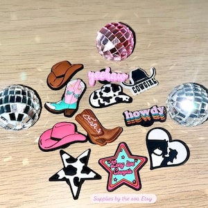 Könnte beinhalten: Eine Sammlung von 12 bunten und lustigen Schuhcharms mit Cowboyhüten, Stiefeln, Sternen, Herzen und Wörtern wie "Howdy" und "Yeehaw".