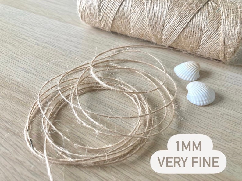 May include: A close-up of a spool of natural twine, 1 mm thick, labeled "1 MM VERY FINE". The twine is very thin and delicate, perfect for crafts and projects.