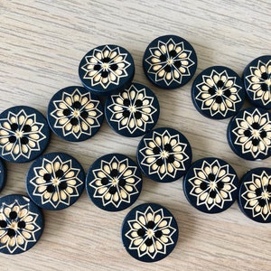 May include: A collection of 15 black round buttons with a gold floral design. The buttons are arranged in a semi-circle pattern.
