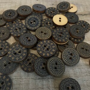May include: A pile of wooden buttons with a dark blue and gold patterned design. The buttons are round and have two holes.