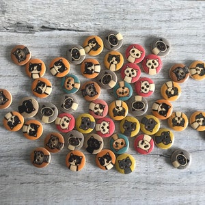May include: A collection of colorful wooden buttons featuring various cat designs. The buttons are round and have a flat back. They are perfect for adding a whimsical touch to crafts and sewing projects.