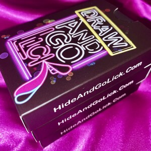 K&ouml;nnte beinhalten: Eine schwarze Box mit neongelben und blauen Buchstaben, auf der "Draw And Go Lick" und "HideAndGoLick.com" steht.