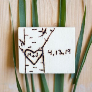 May include: A wooden plaque with a heart and the initials "M+J" burned into it. The date "4.13.19" is also burned into the plaque.