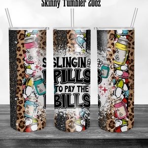 May include: A black and white tumbler with a leopard print design and the text "Slingin' Pills to Pay the Bills". The tumbler is filled with colorful pills and has a white glitter background.
