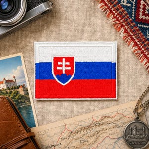 May include: Embroidered patch depicting the flag of Slovakia. The rectangular patch has a white border and shows the flag's horizontal stripes of white, blue, and red, with the Slovak coat of arms in the centre. The coat of arms is a white double cross on a blue shield.