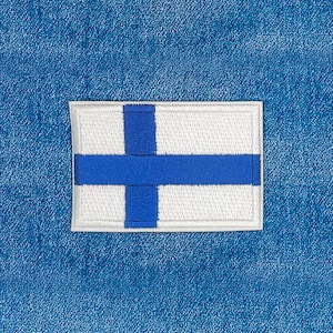 May include: A rectangular patch featuring the flag of Finland, with a white background and a blue Nordic cross. The patch is bordered by a white stitched edge and is set against a blue denim background.
