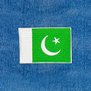 May include: Embroidered patch featuring the flag of Pakistan. The flag has a white vertical stripe on the left, a green field with a white crescent moon and star. The patch is rectangular with a white border.
