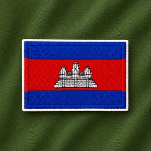 May include: A rectangular embroidered patch featuring the flag of Cambodia. The design consists of a wide red horizontal band in the center with a white illustration of the Angkor Wat temple, flanked by two blue horizontal bands, all bordered in white.